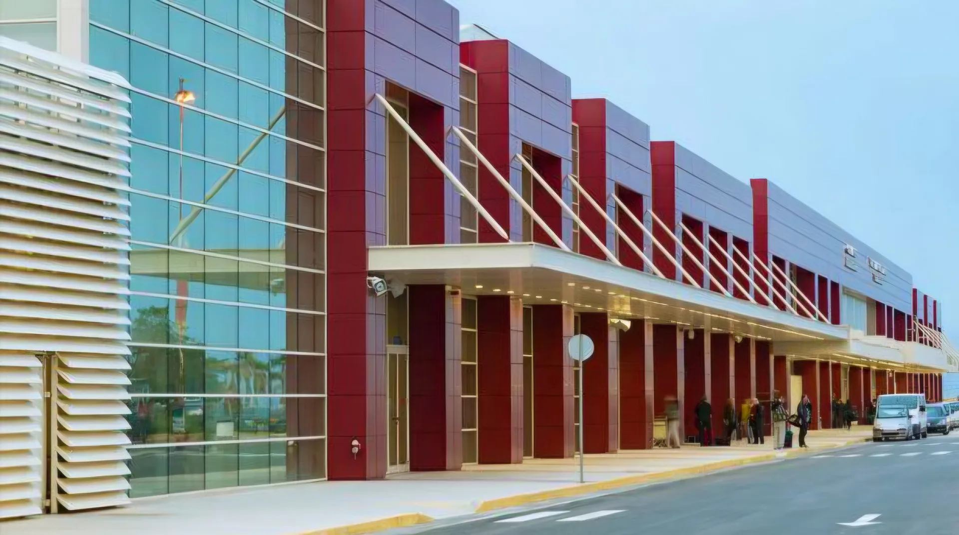 The terminal's glass façade, canopy and red panels along the kerb